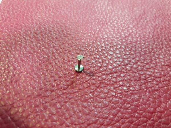 titanieva-obeca-za-ustna-labret-opal Титаниева обеца за устна с малък блестящ опал върху розова кожена повърхност