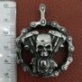 Рокерско колие с череп от стомана и мото верига Заглавие на снимка: rokersko-kolie-s-cherep-ot-stomana-biker Описание на снимка: Кръгъл сребрист медальон от патинирана стомана с детайлен череп, моторен двигател и мото верига, заснет до разграфена линийка.