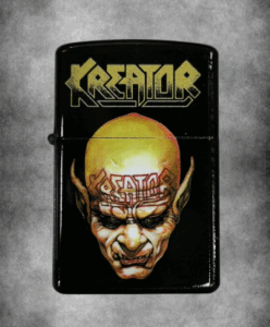 Черна бензинова запалка с жълто лого на Kreator и изображение на гротесков демон с изпъкнал череп.