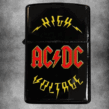 Черна бензинова запалка с червено-жълто лого на AC/DC и надписите HIGH VOLTAGE с мълнии.